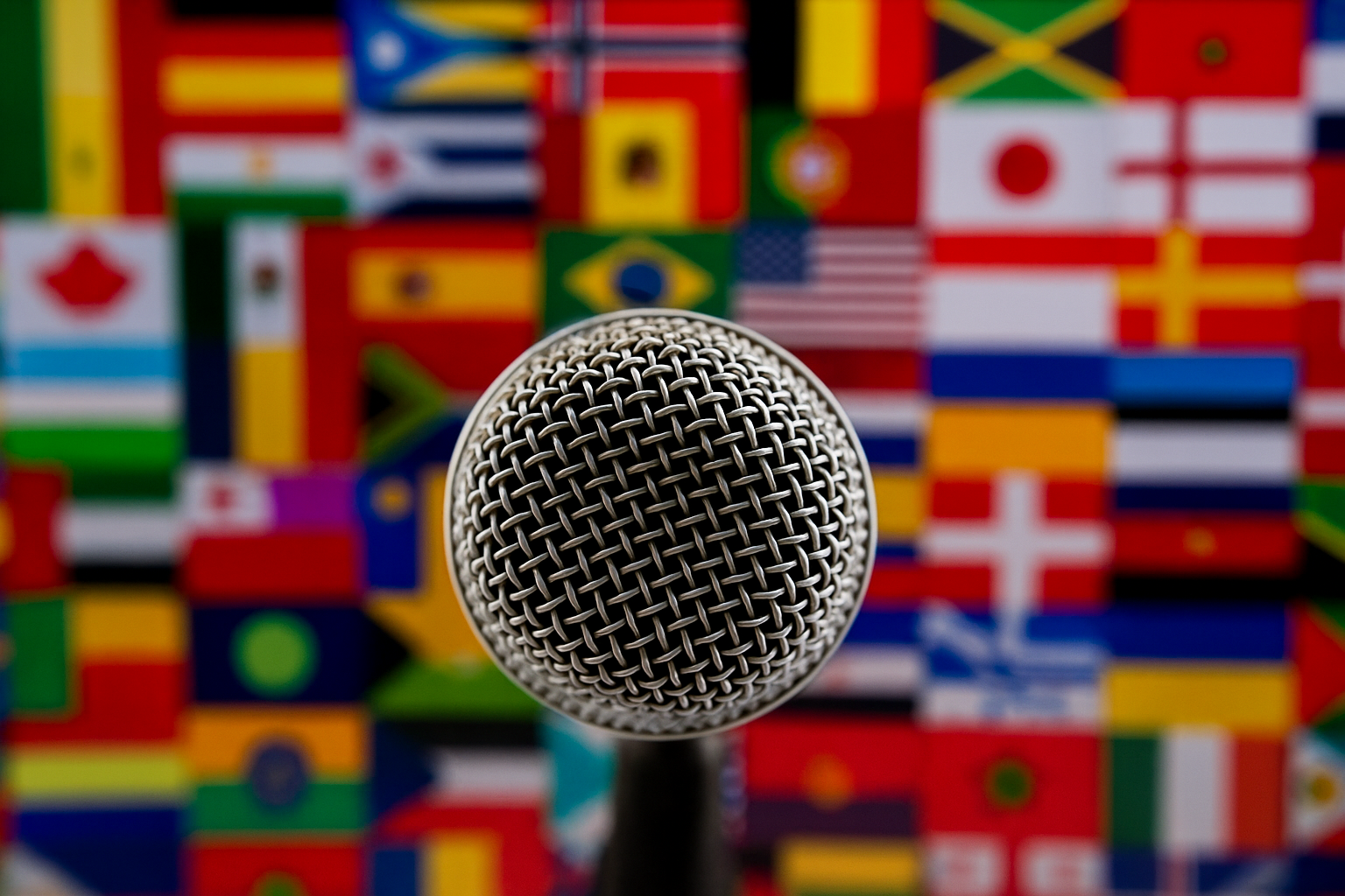 Micrófono con fondo de banderas internacionales que simboliza locuciones en múltiples idiomas y acentos.